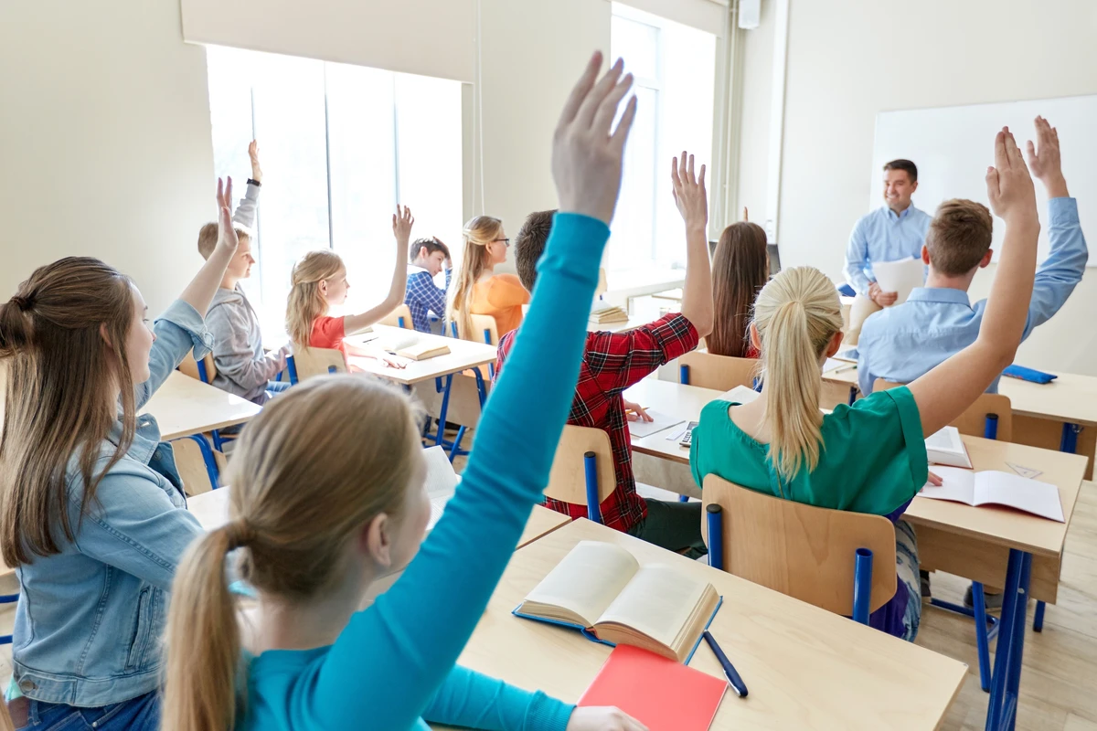 Students raising their hands in a classroom